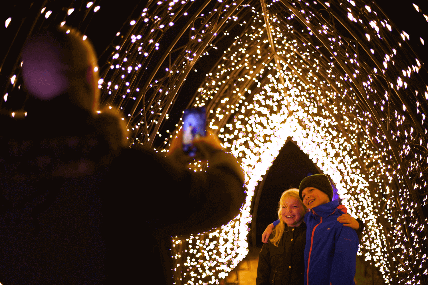 A family take a photo in the light tunnel at Marwell Zoo's Glow Marwell festive event