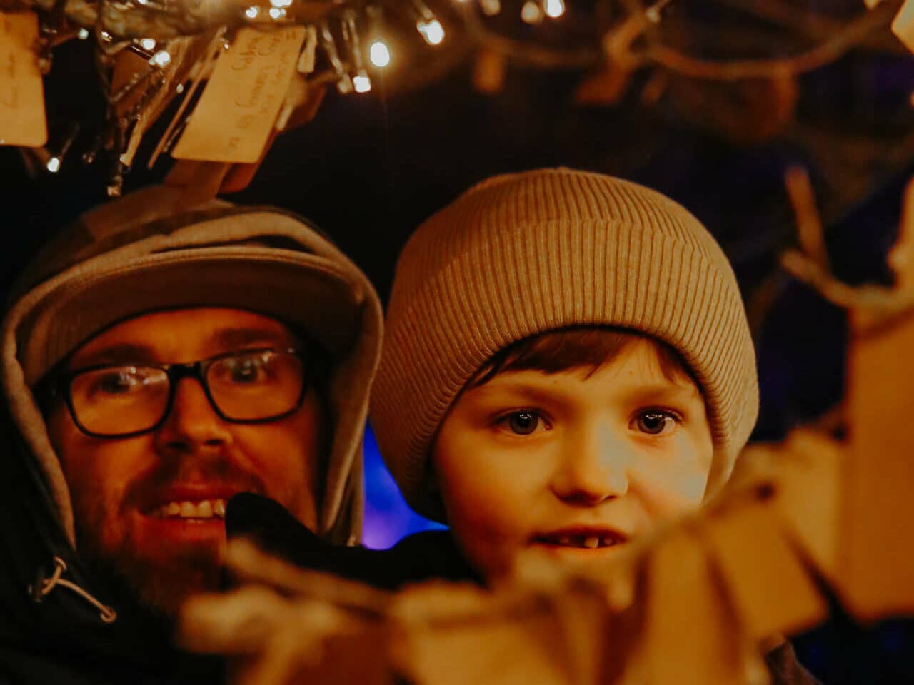 A father and son add a wish to the wishing tree at glow Marwell, Marwell Zoo