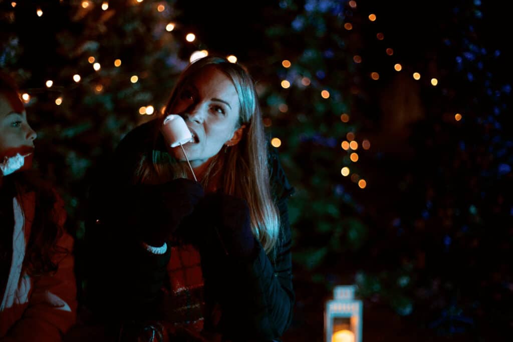 A woman eats a toasted marshmallow at Glow Marwell