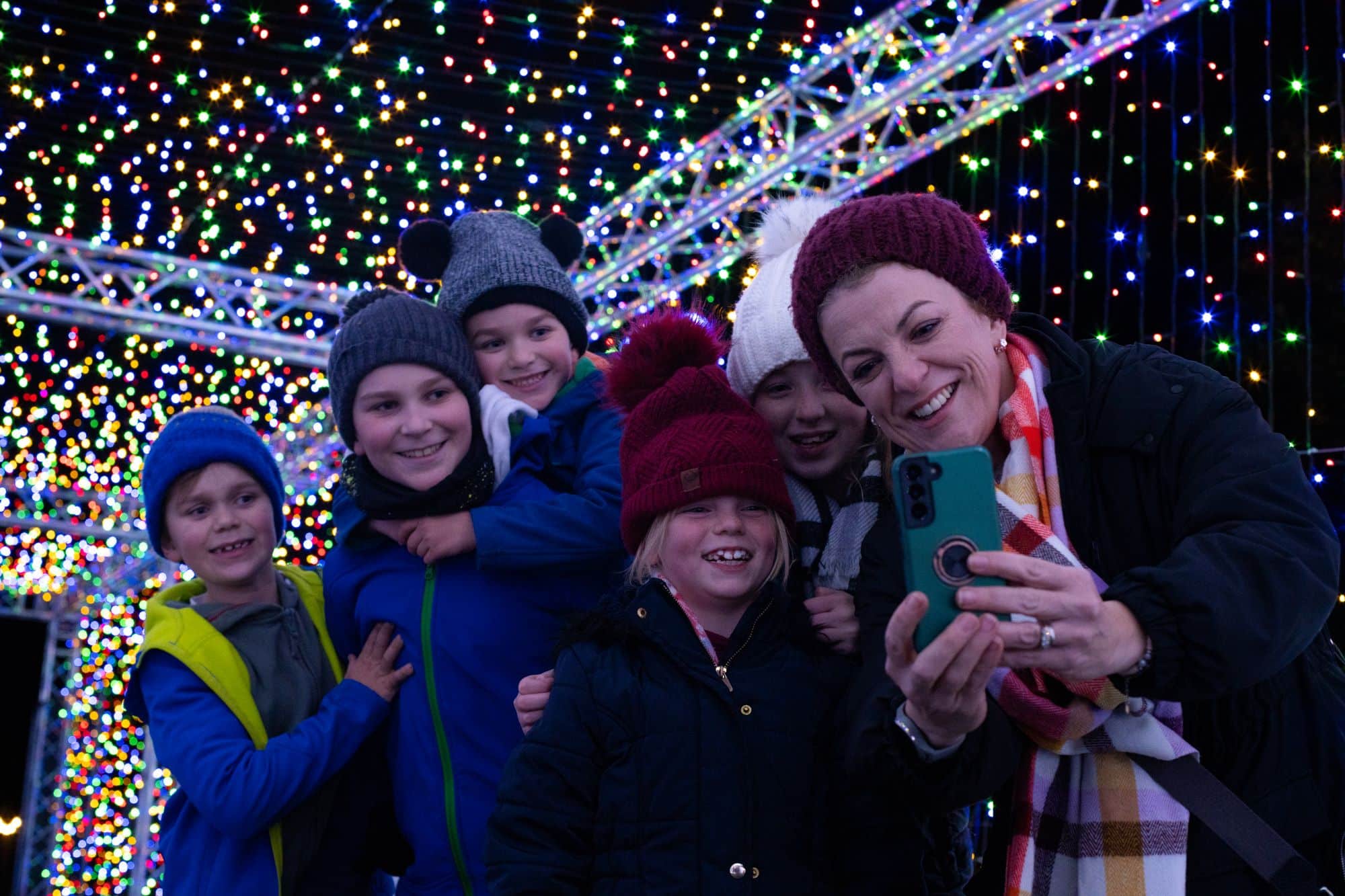 Children and a parent take a selfie inside the rainbow light tunnel at Glow Marwell 2023