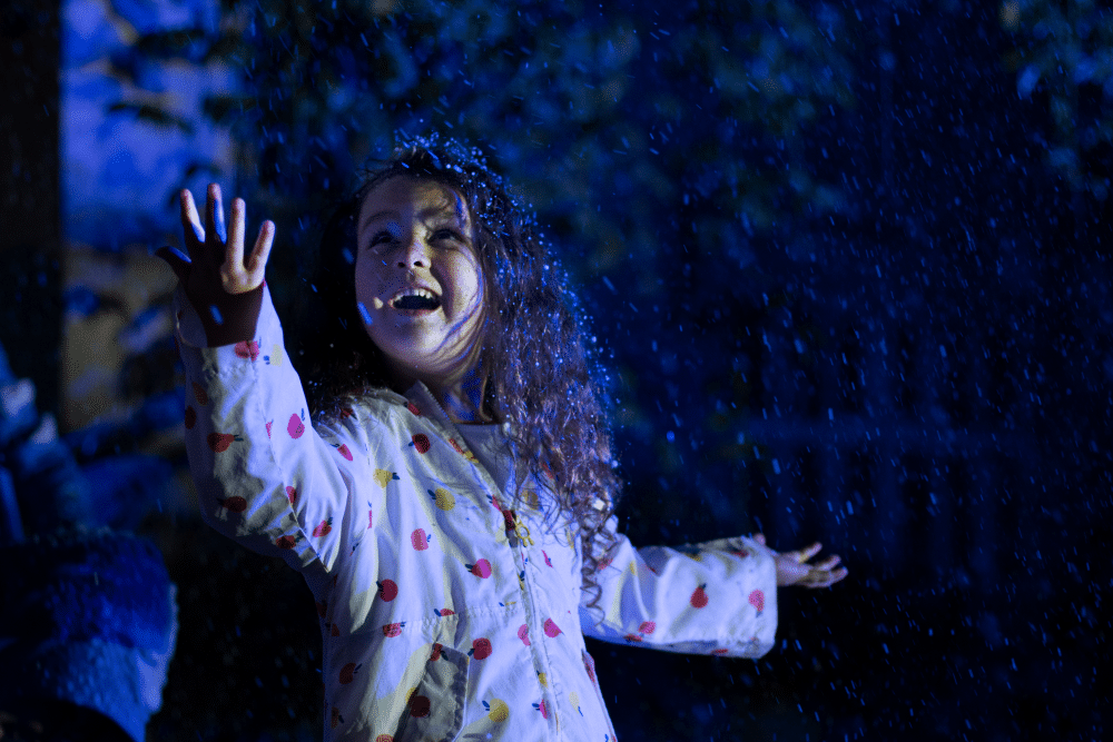 A little girl marvels at snow as it falls around her at Glow Marwell 2023