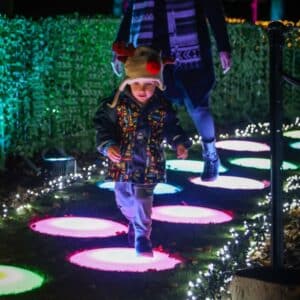 A child hops across stepping stones at Glow Marwell christmas light trail event
