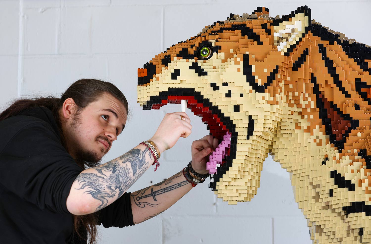 A man builds a sculpture out of toy bricks