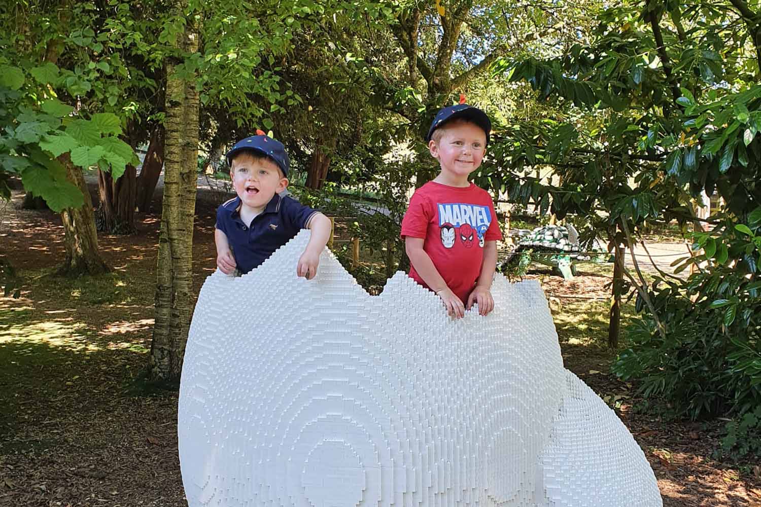 Two children pose in a dinosaur egg made from toy bricks