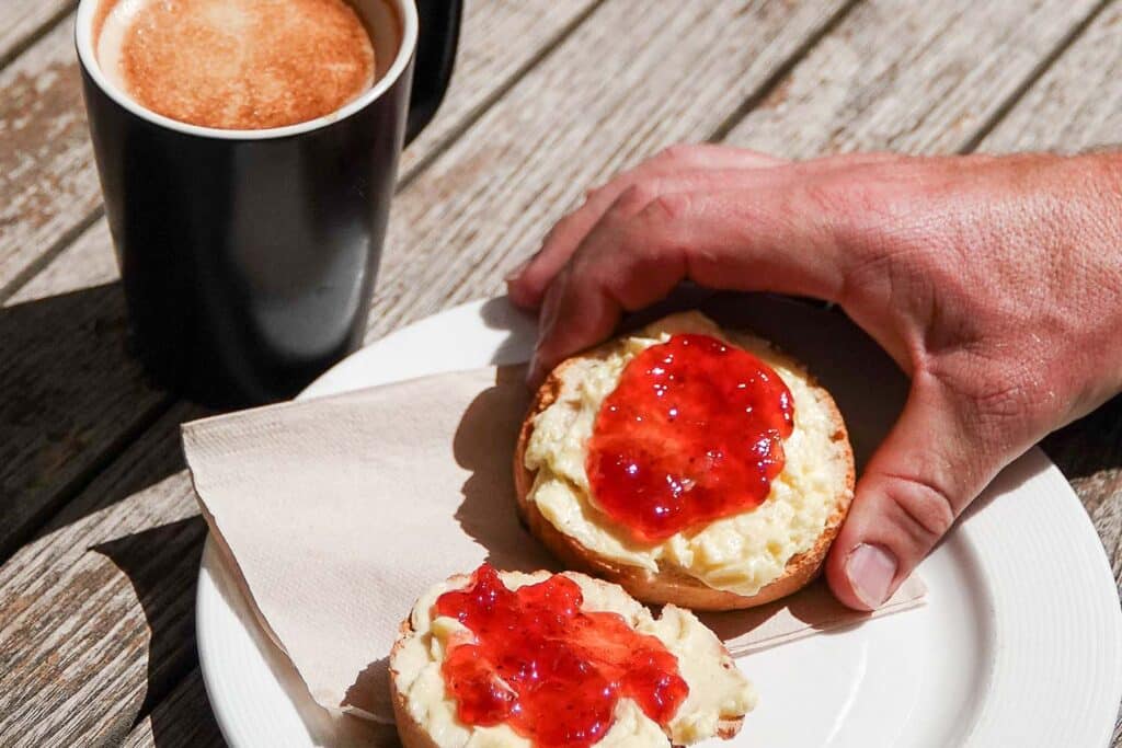 Someone picking up a scone with jam and cream at The Keeper's Kitchen at Marwell Zoo