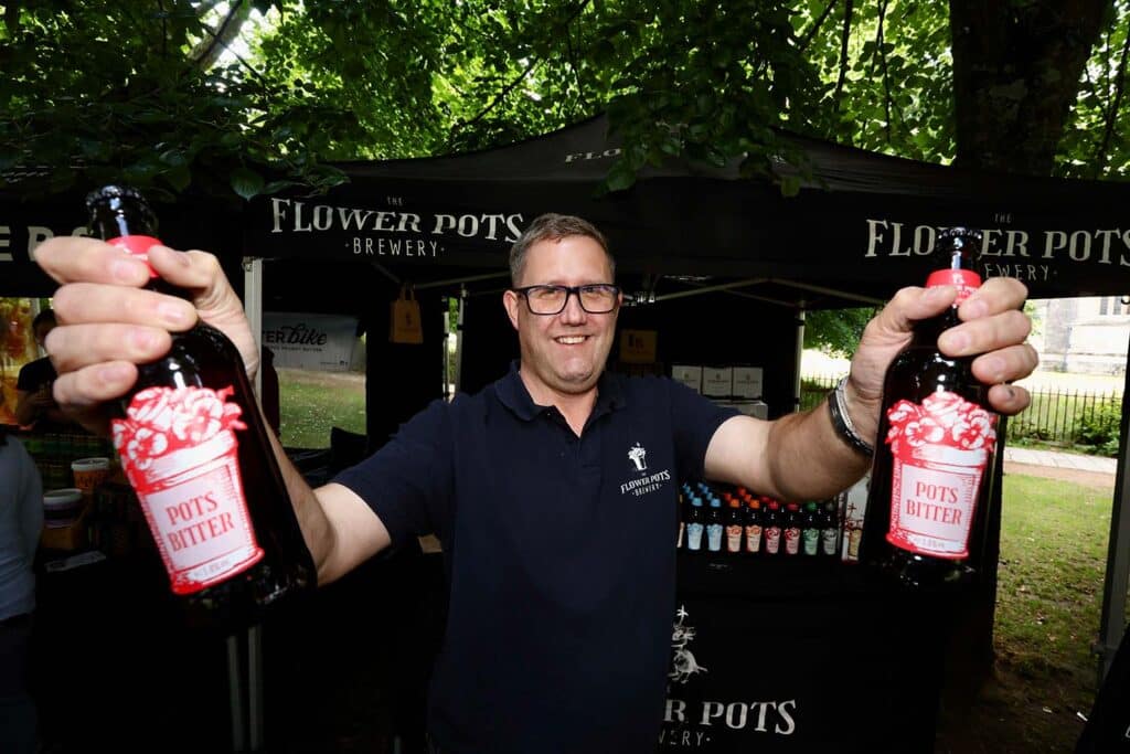 A Flower Pots Brewery team member holds up bottles of Pots Bitter at a Hampshire Food Festival