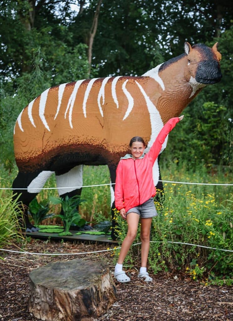 A girl poses with a moropus made of toy bricks at Marwell Zoo's Extinction event