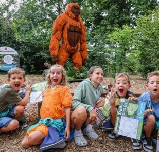 A group of children pose in front of a Gigantopithecus made from toy bricks at Marwell Zoo's Extinction event