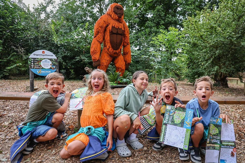 A group of children pose in front of a Gigantopithecus made from toy bricks at Marwell Zoo's Extinction event