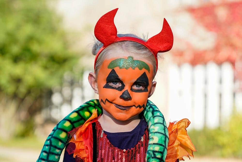 A girl with her face painted as a pumpkin at Marwell Zoo