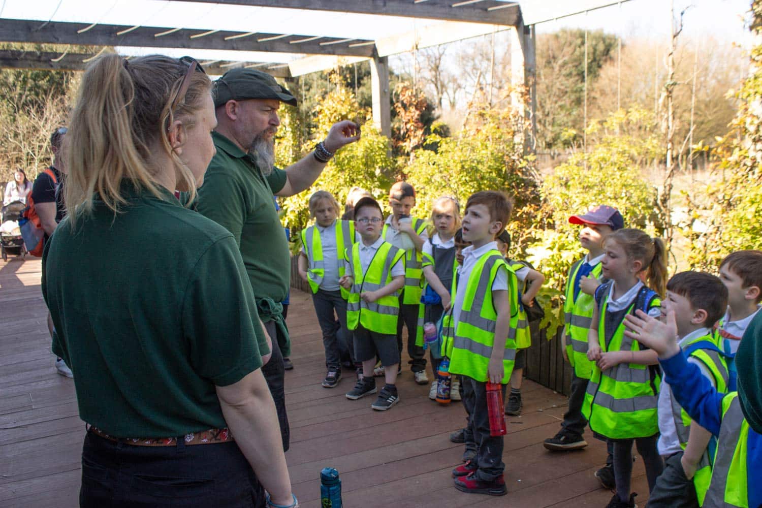 A group of school children listen while two Marwell Zoo educators speak to them outside the Tropical House