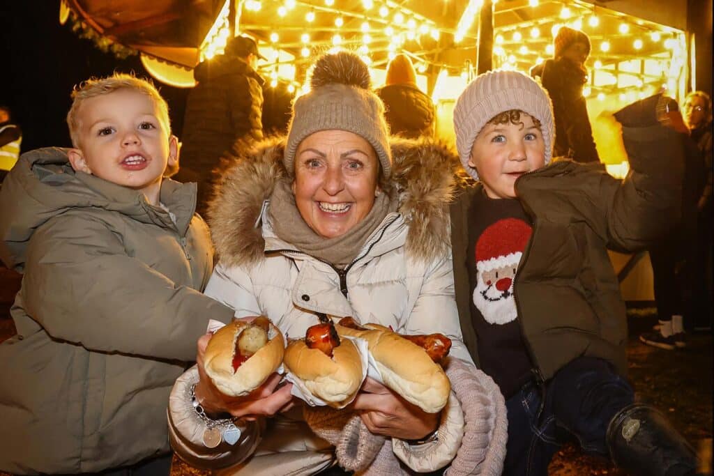 A family with bratwurst at the Glow Marwell winter light trail at Marwell Zoo