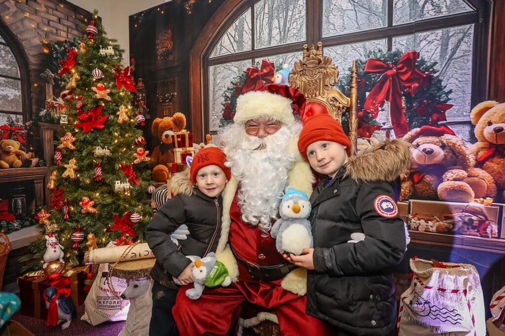 Two children with Father Christmas at the Christmas at Marwell Hall grotto experience