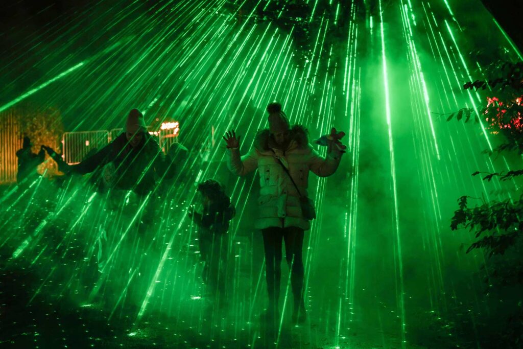 A family play in the laser light show at Glow Marwell at Marwell Zoo