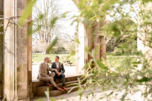 A wedding couple sit on the steps of Marwell Hall