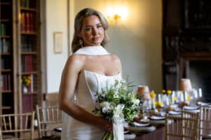 A bride holding a bouquet of flowers poses for photos in the Seymour Library