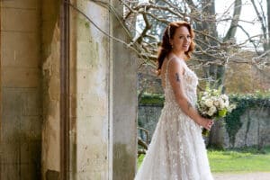 A bride holding a bouquet of flowers poses for photos in front of Marwell Hall