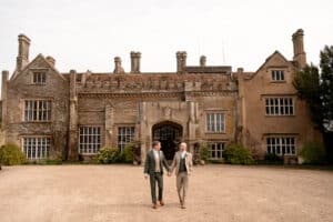 A couple hold hands in front of Marwell Hall on their wedding day