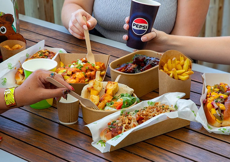 Guests enjoying a selection of food from Cafe Graze, including hot dogs, fries and halloumi skewers