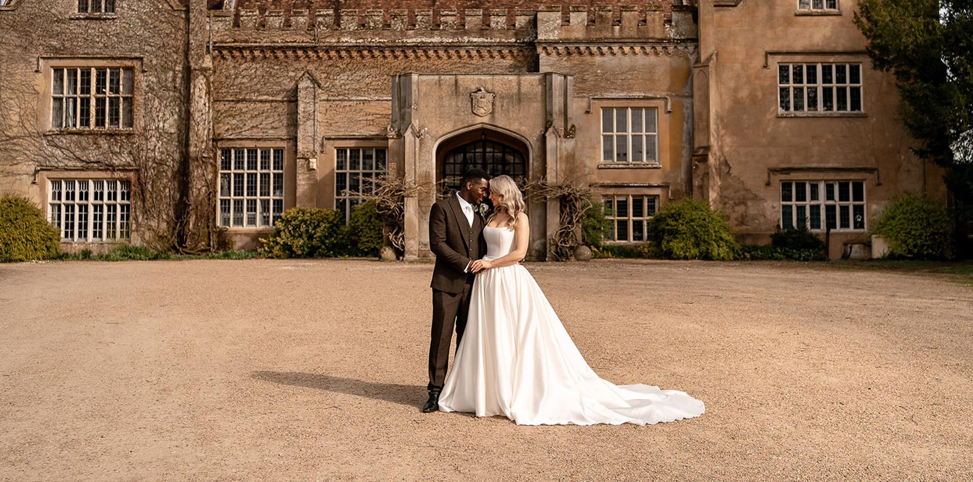 A couple embrace outside Marwell Hall on their wedding day