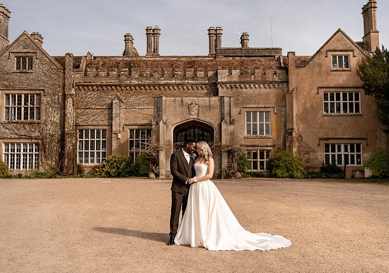 A couple embrace outside Marwell Hall on their wedding day