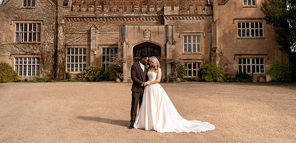 A couple embrace outside Marwell Hall on their wedding day
